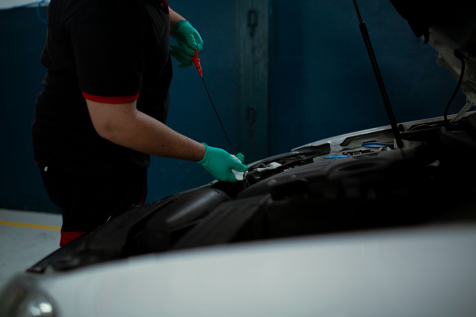 Mechanic in gloves checking the engine oil level with a dipstick