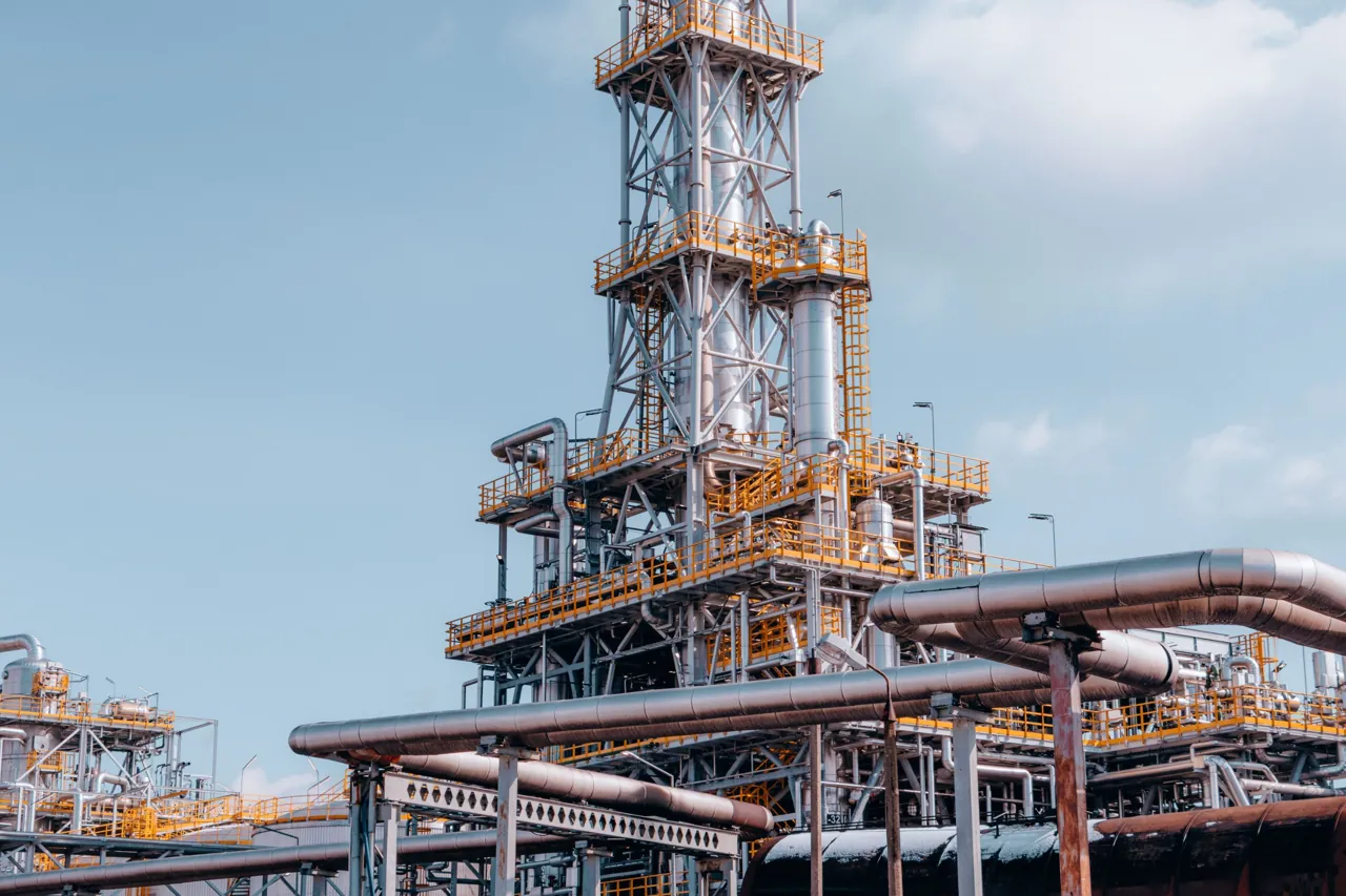 Refinery distillation tower with yellow safety walkways and insulated pipe racks
