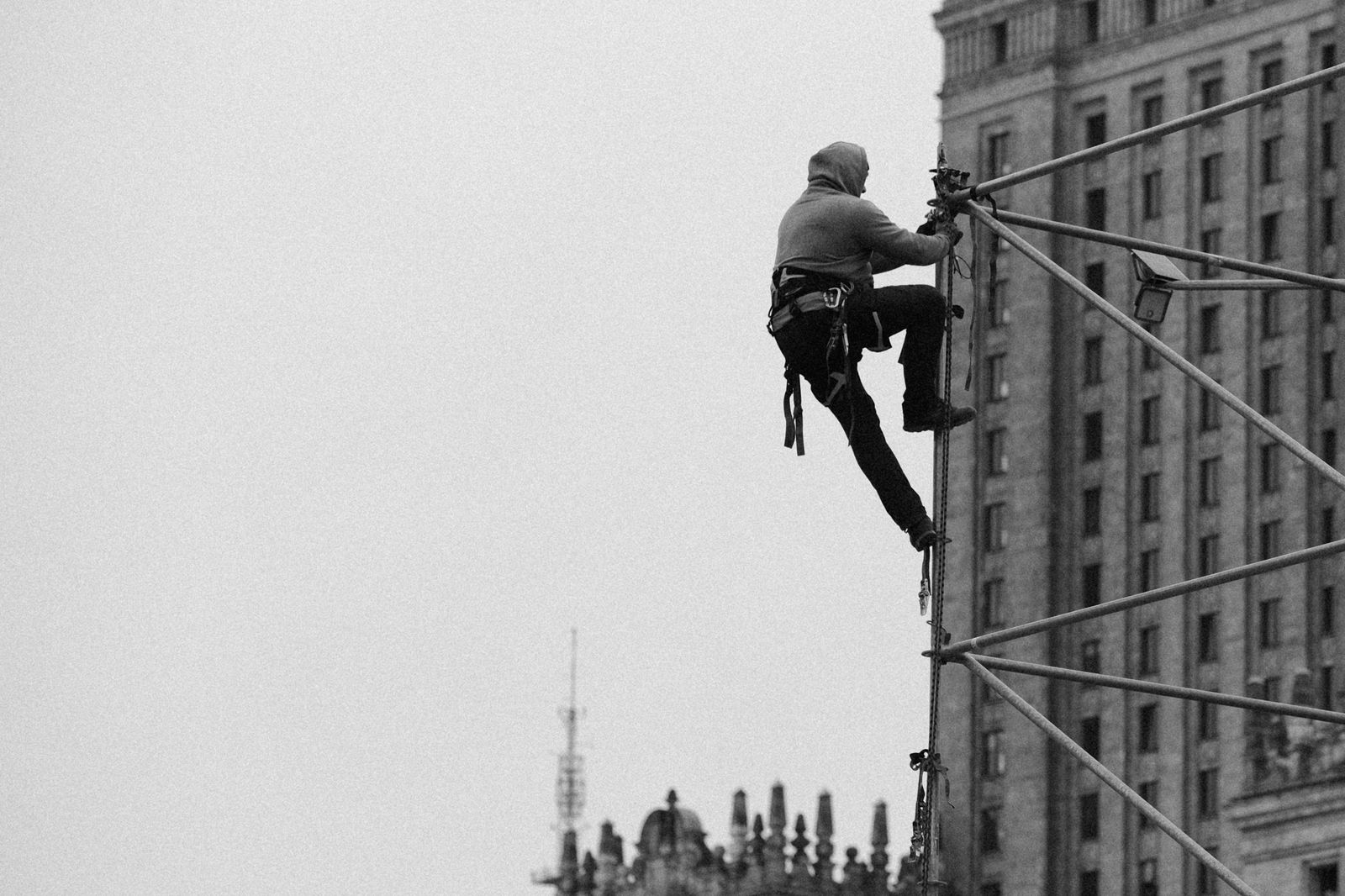 Worker wearing a full body harness climbing a temporary steel structure
